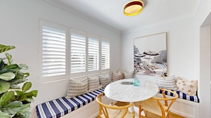 A room with a round table, bench seating, and a large framed picture on the wall. - Coogee by the Coast  (Coogee)