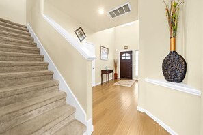 Eine Treppe führt zu einer Zwischenebene mit einer Tür und einer Vase auf einem Regal.