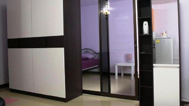Una camera da letto con un letto, una scrivania bianca, un armadio e uno specchio.