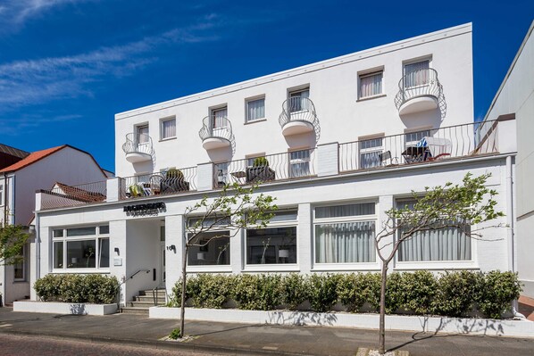 A white building with multiple balconies, large windows, and a small entrance. - Doppelzimmer Economy - Logierhaus am Rathaus (Norderney)