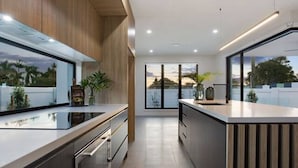 A modern kitchen with a large window, wooden cabinetry, and a sleek countertop.