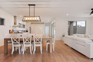 Une cuisine moderne avec un coin repas, un canapé blanc et un ventilateur de plafond.