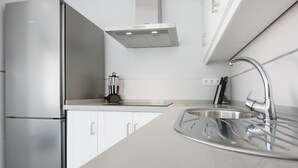 Een moderne keuken met een roestvrijstalen koelkast, een inbouwoven, een roestvrijstalen spoelbak en een afzuigkap.