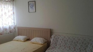 Un dormitorio con cama, sofá, un cuadro en la pared y una ventana con cortinas florales.