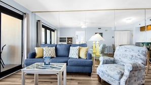 A living room with a blue sofa, patterned armchair, and a glass coffee table.