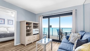 A modern living room with a balcony, a wicker sideboard, a sofa, and a bed.