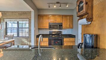 A kitchen with wooden cabinets, a stainless steel microwave, a stove, and a sink.