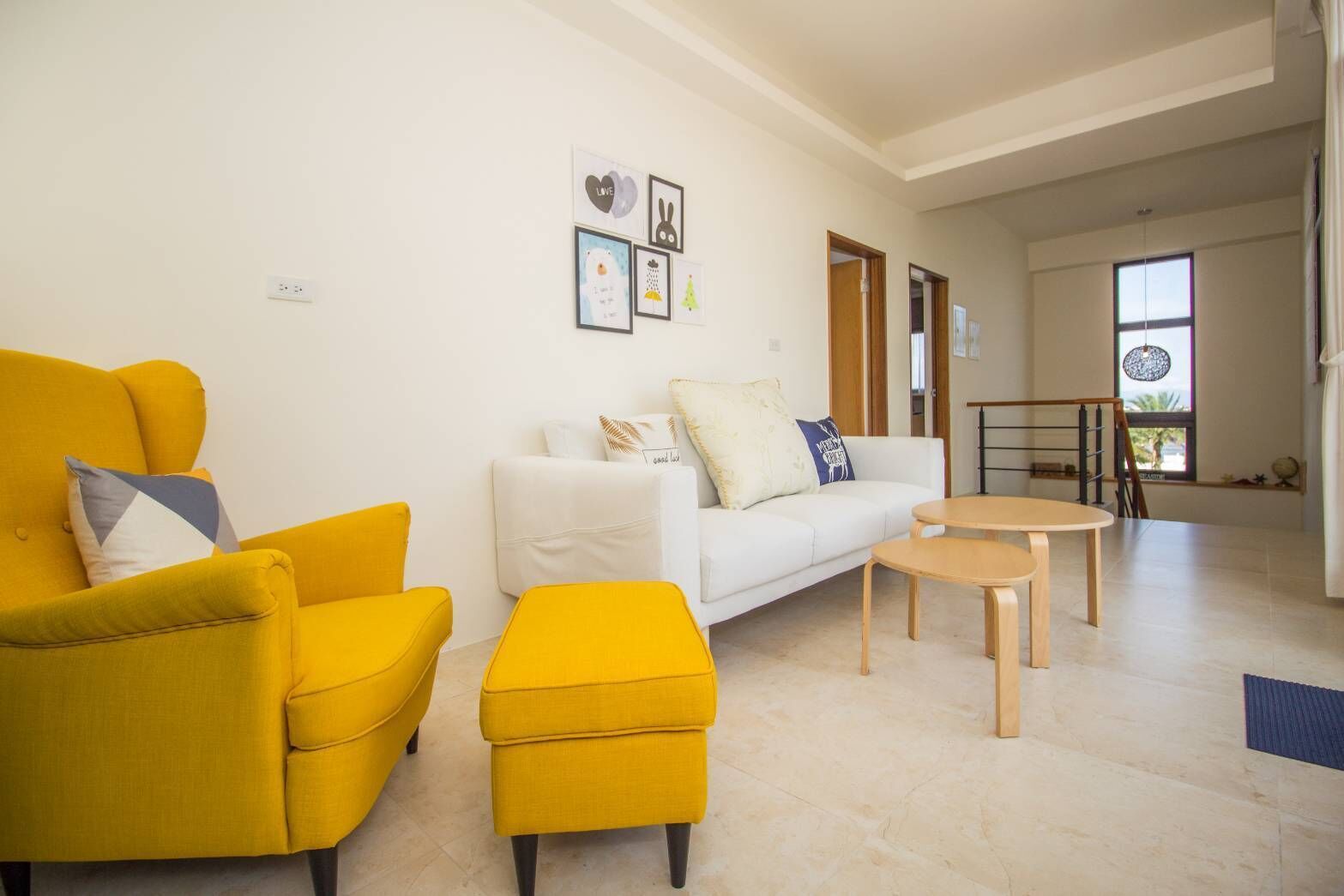 A modern living room with a yellow sofa set, a white sofa, and a small wooden table.