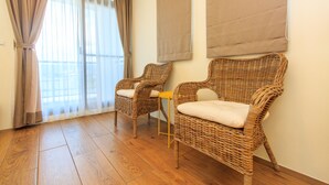 A room with two wicker chairs, a small table, and a view through a window with curtains. - Classic Villa B&B (Dongshan)