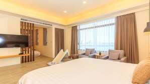 A hotel room with a large bed, a flat-screen TV, a sofa, a small table, and a window with curtains. - Classic Villa B&B (Dongshan)