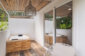 Uma casa de banho moderna com uma banheira de madeira, uma pia branca e uma luminária pendente de vime.