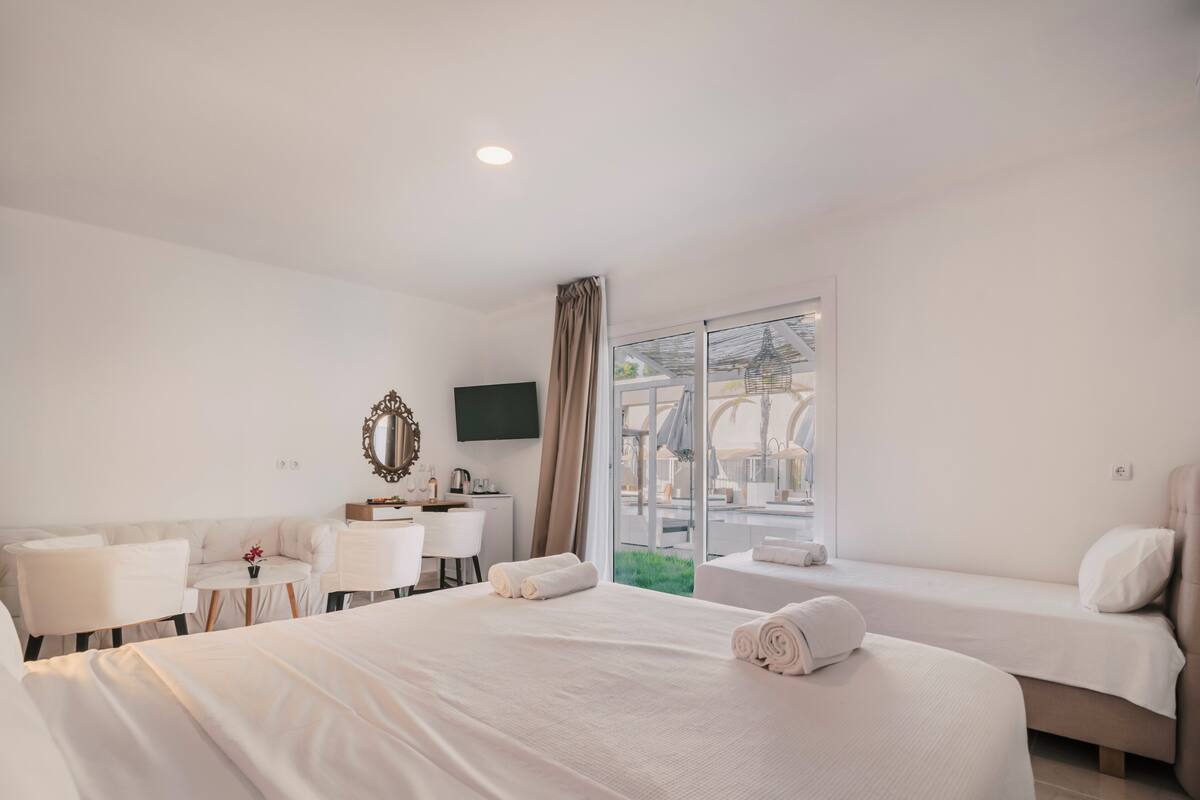 Habitación de hotel con una cama grande, un escritorio, una silla, una mesita y un televisor.