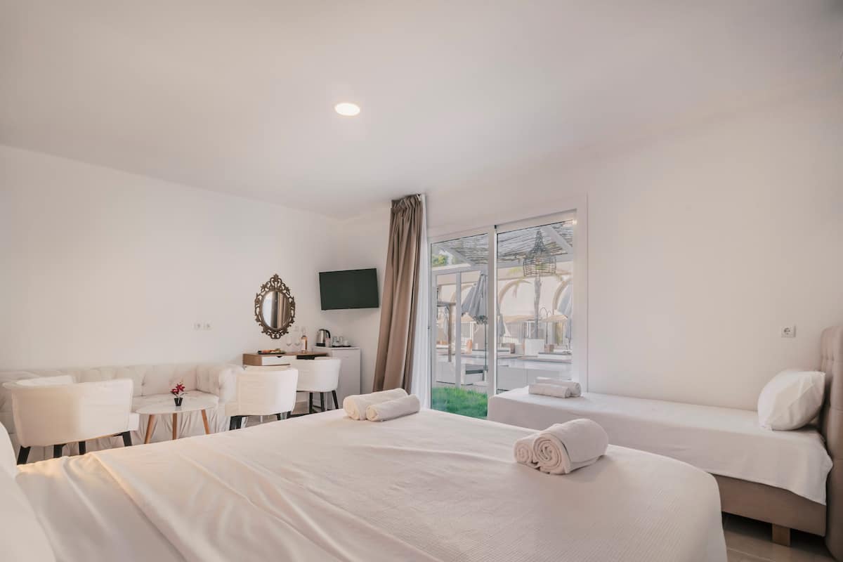 A hotel room with a large bed, a desk, a chair, a small table, and a TV.