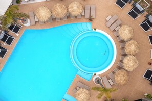 Uma grande piscina ao ar livre com espreguiçadeiras e guarda-sóis dispostos ao redor.