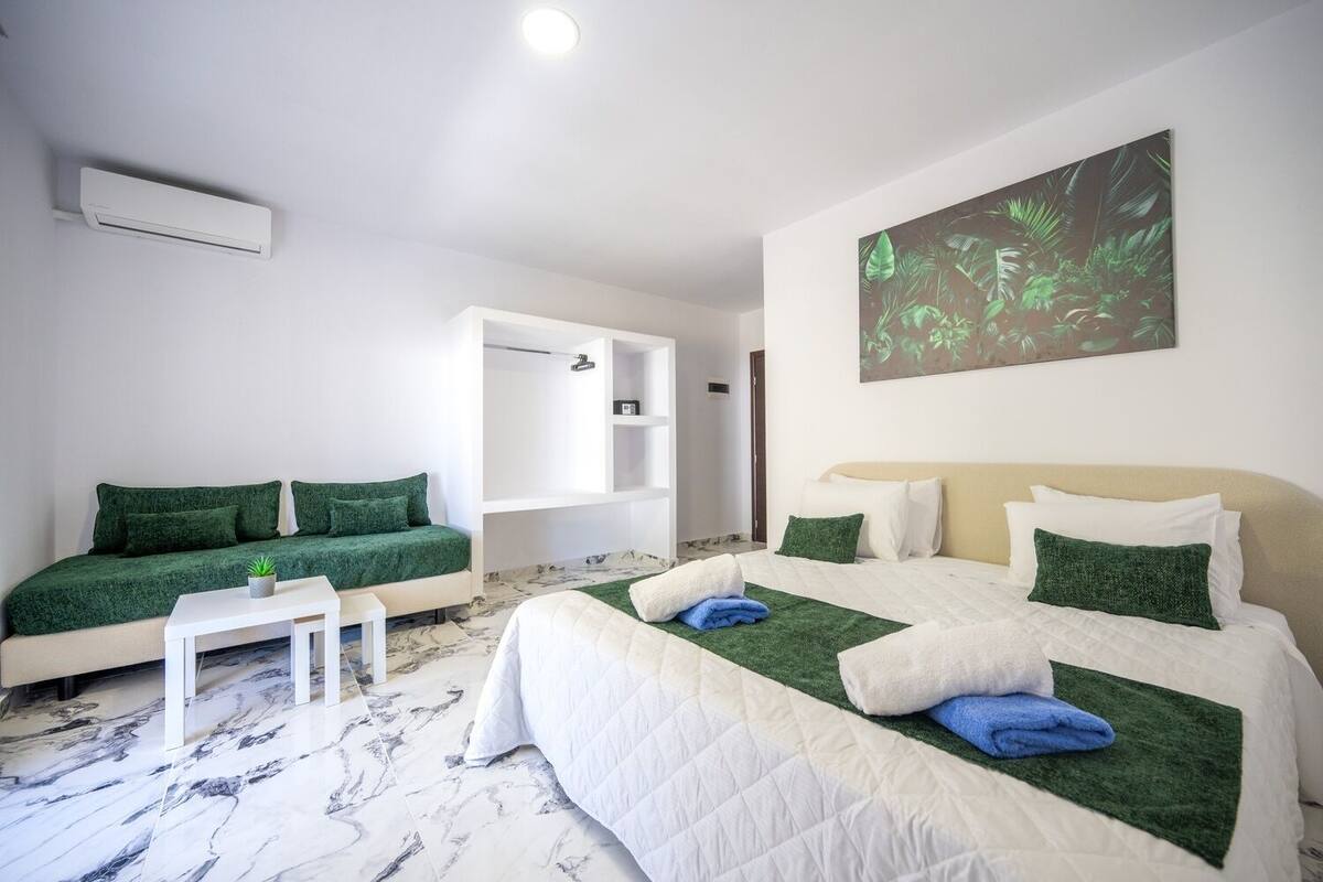 Una habitación de hotel con una cama, un sofá, una mesita y un cuadro en la pared.