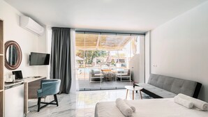 Habitación de hotel moderna con cama, escritorio, televisión y vistas a un área de piscina al aire libre.