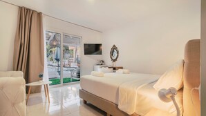 Habitación de hotel con cama, una silla, una mesita, televisor y vistas al exterior.