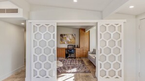 A modern interior with a geometric-patterned door leading to a living area, a kitchen, and a bedroom. - Mid-Century Beauty! Community Pool! Hiking! Mountain Views! Walk to El Paseo! (Palm Desert)