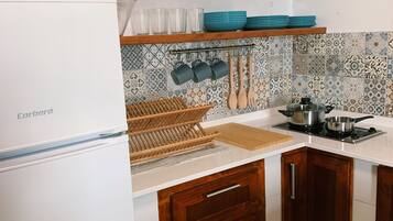 Een koelkast, kookgerei, borden en bestek