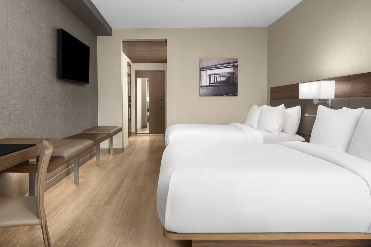 A hotel room with a bed, a desk, and a TV.