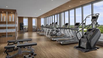 Une salle de sport moderne équipée de tapis de course, de vélos elliptiques et d’appareils de musculation.
