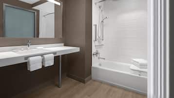 A modern bathroom with a white sink, mirror, and bathtub.