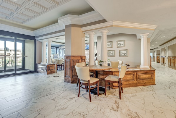 A spacious dining area with a marble floor, wooden furniture, and a view through a glass door.