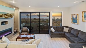 A spacious living room with a fireplace, a large sofa, and a dining area. - Newly remodeled home with breathtaking ocean view. (Newport Beach)