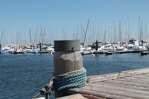 Ein Holzsteg mit einem an einem Pfahl befestigten Seil, eine Marina mit mehreren Booten und ruhigem Wasser.
