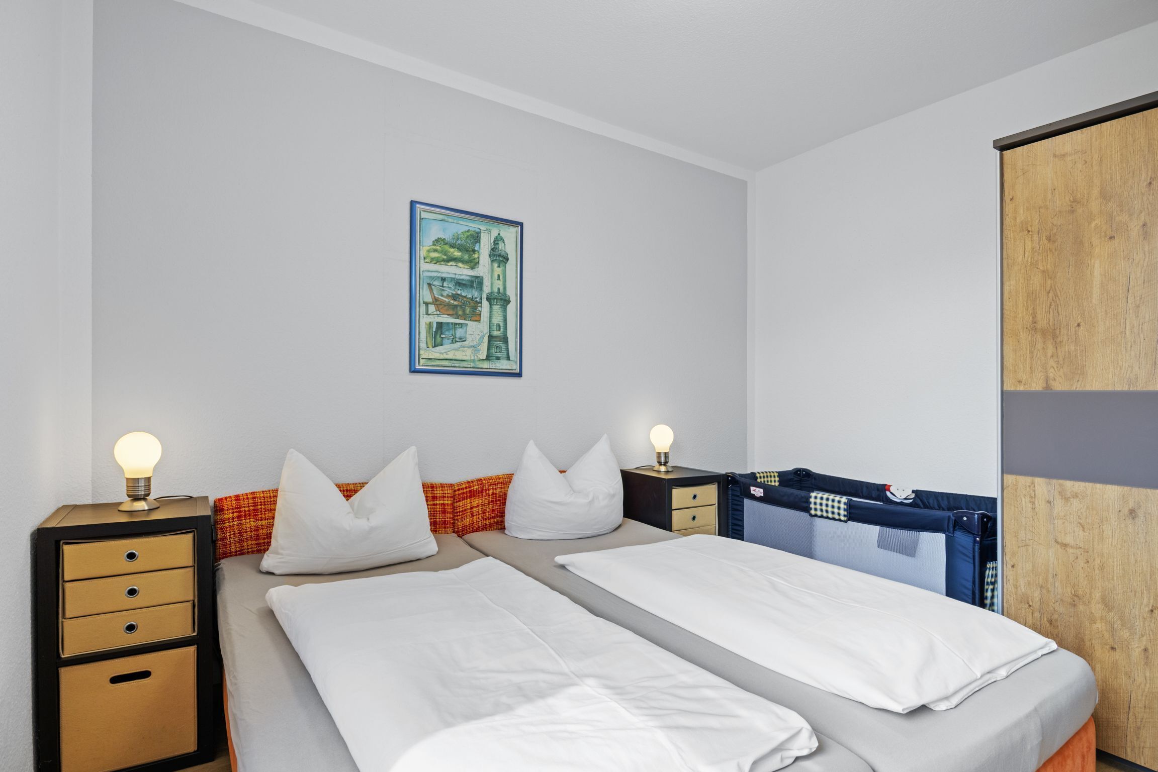 Una camera da letto con due letti, un comodino con cassetti, una lampada e un quadro appeso al muro.