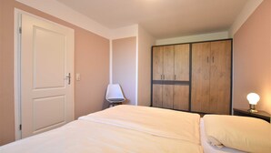 Ein Schlafzimmer mit Bett, Kleiderschrank, Lampe und Nachttisch.