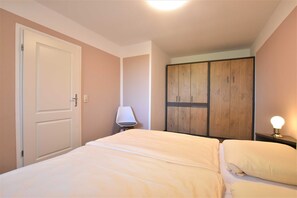 Una camera da letto con un letto, un armadio, una lampada e un comodino.