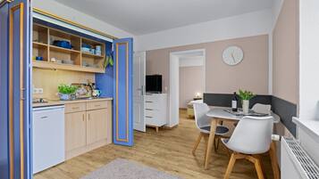 Ein kompakter Wohnraum mit Küchenzeile, Essbereich und Fernseher.