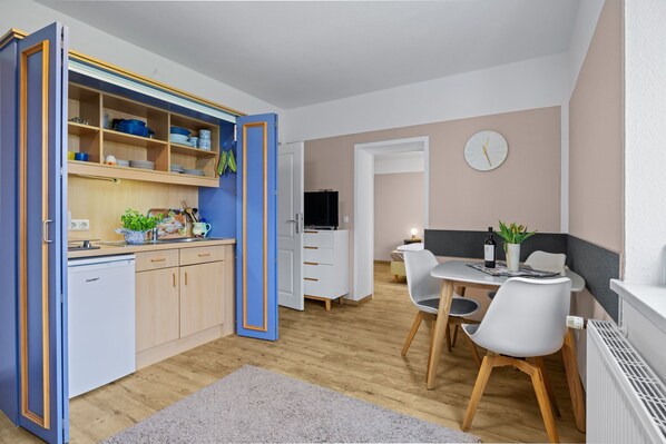 Un espace de vie compact comprenant une kitchenette, un coin repas et un téléviseur.