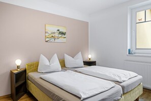 Ein Schlafzimmer mit zwei Betten, einem Nachttisch mit Lampe, einem Bild an der Wand und einem Fenster mit Aussicht.