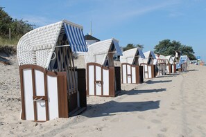 Een rij strandhutten met gestreepte luifels, langs een zandstrand gelegen.