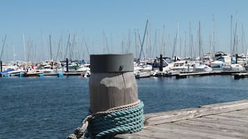 Ein Holzsteg mit einem an einem Pfahl befestigten Seil, eine Marina mit mehreren Booten und ruhigem Wasser.