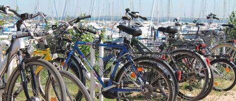 Fietsen op een rij, een jachthaven met boten op de achtergrond en een heldere lucht.