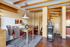 Een eetgedeelte met een houten tafel, rieten stoelen, een vloerkleed en een moderne hanglamp.