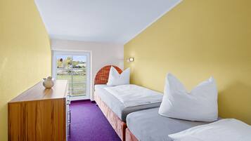 A hotel room with two single beds, a wooden desk, and a purple carpet.