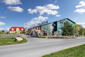 Ein traditionelles Haus mit rotem Dach, blauer Fassade und einer Mauer aus Stein davor.