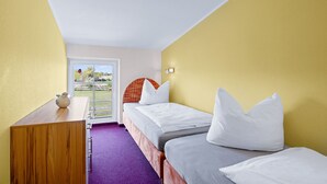 A hotel room with two single beds, a wooden desk, and a purple carpet.
