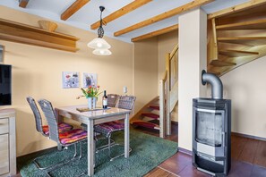 A cozy dining area with a table, chairs, and a wood-burning stove.