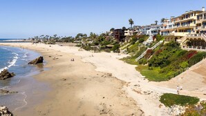 Ein Küstenstrand mit Strandhäusern, darunter mehrstöckige Gebäude mit Balkonen und freiem Blick auf den Ozean.