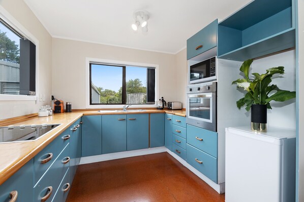 Una cocina moderna con armarios azules, encimera de madera y refrigerador blanco.