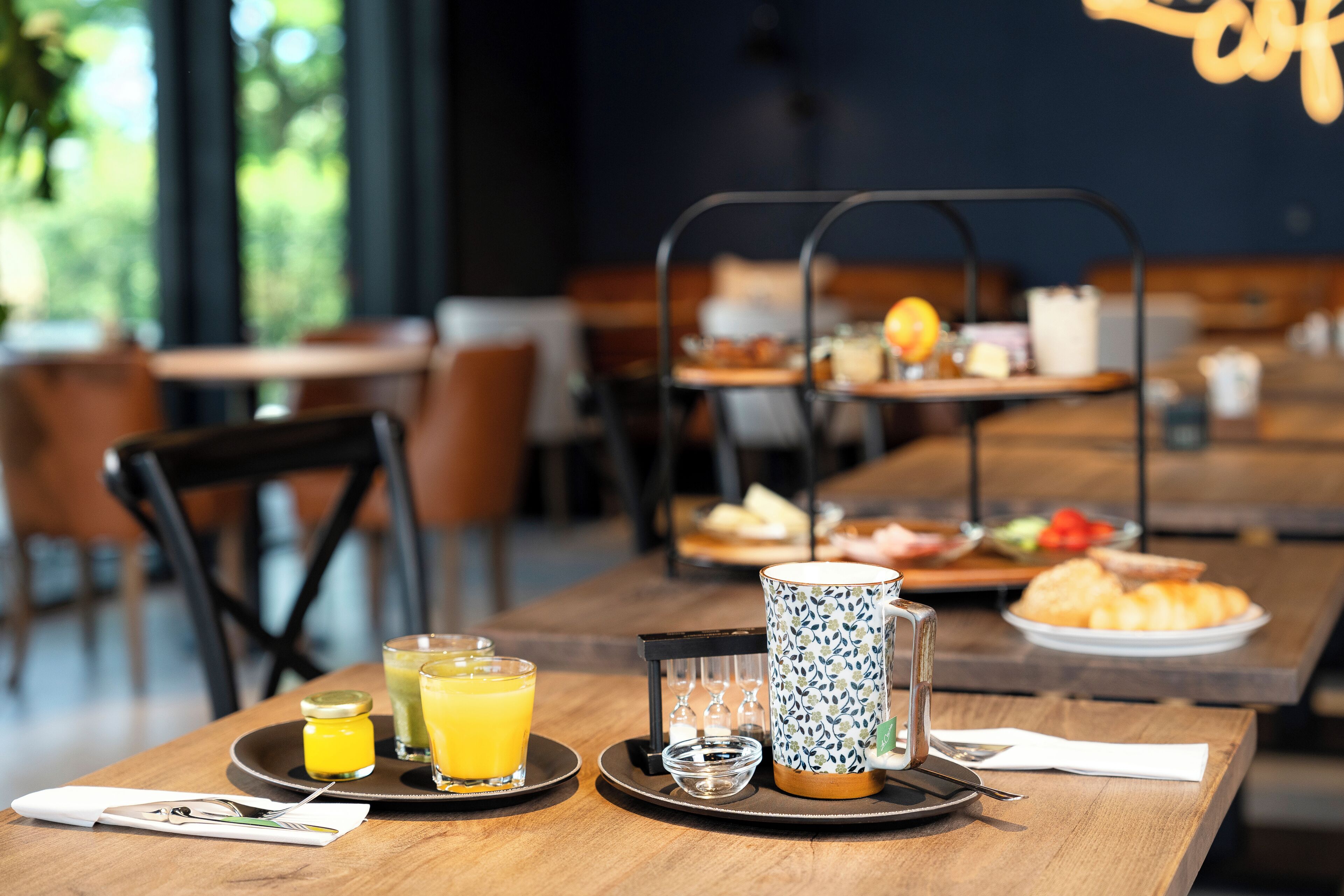 Un plateau de petit-déjeuner comprenant un verre de jus d’orange, une tasse et une assiette avec des croissants.