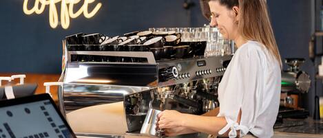 A barista at work, preparing a drink with a coffee machine.