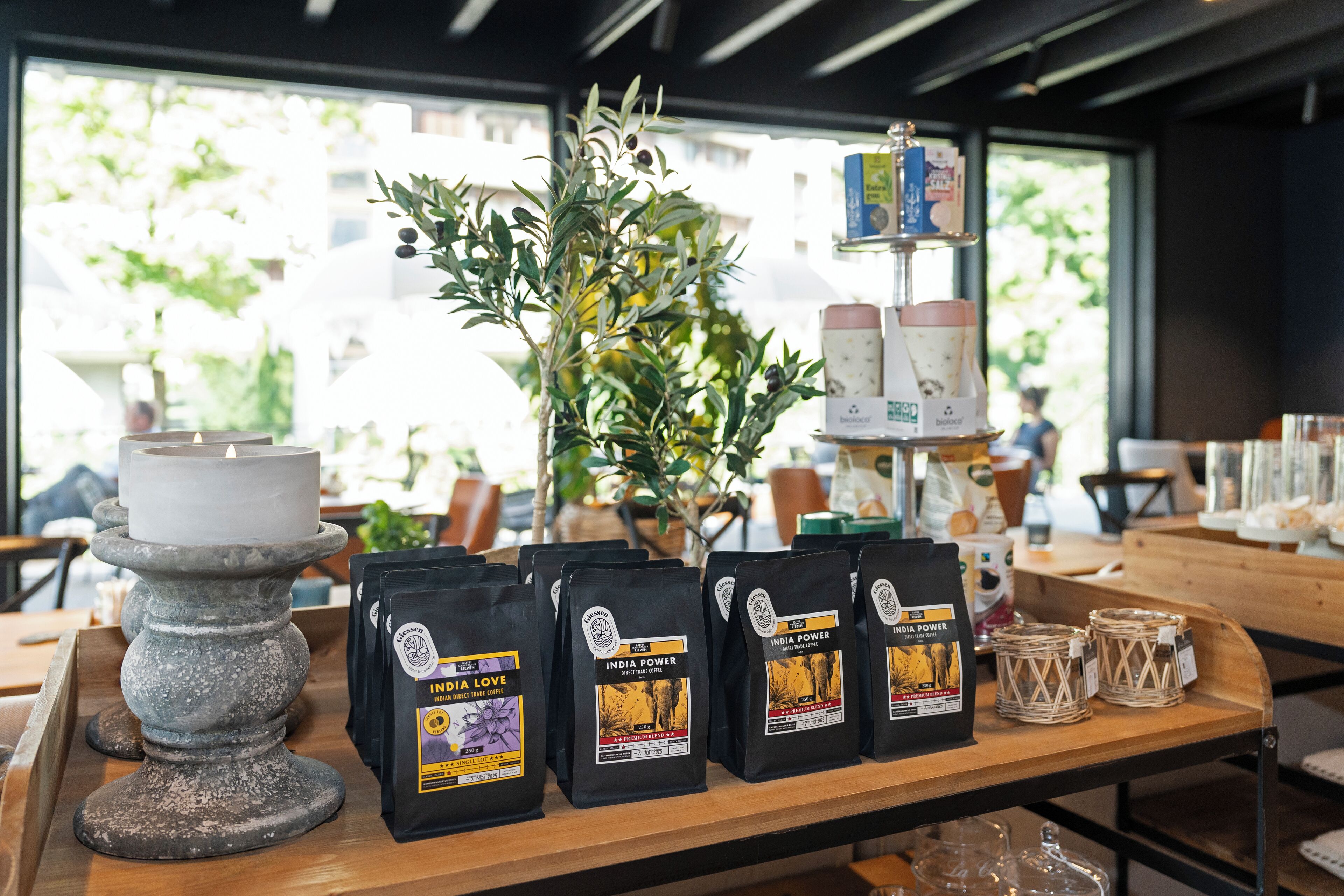 A table with bags of coffee, a candle, and a plant.