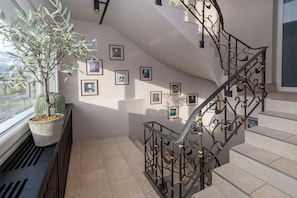 A staircase with ornate metal railings, a potted plant, and framed pictures on the walls.