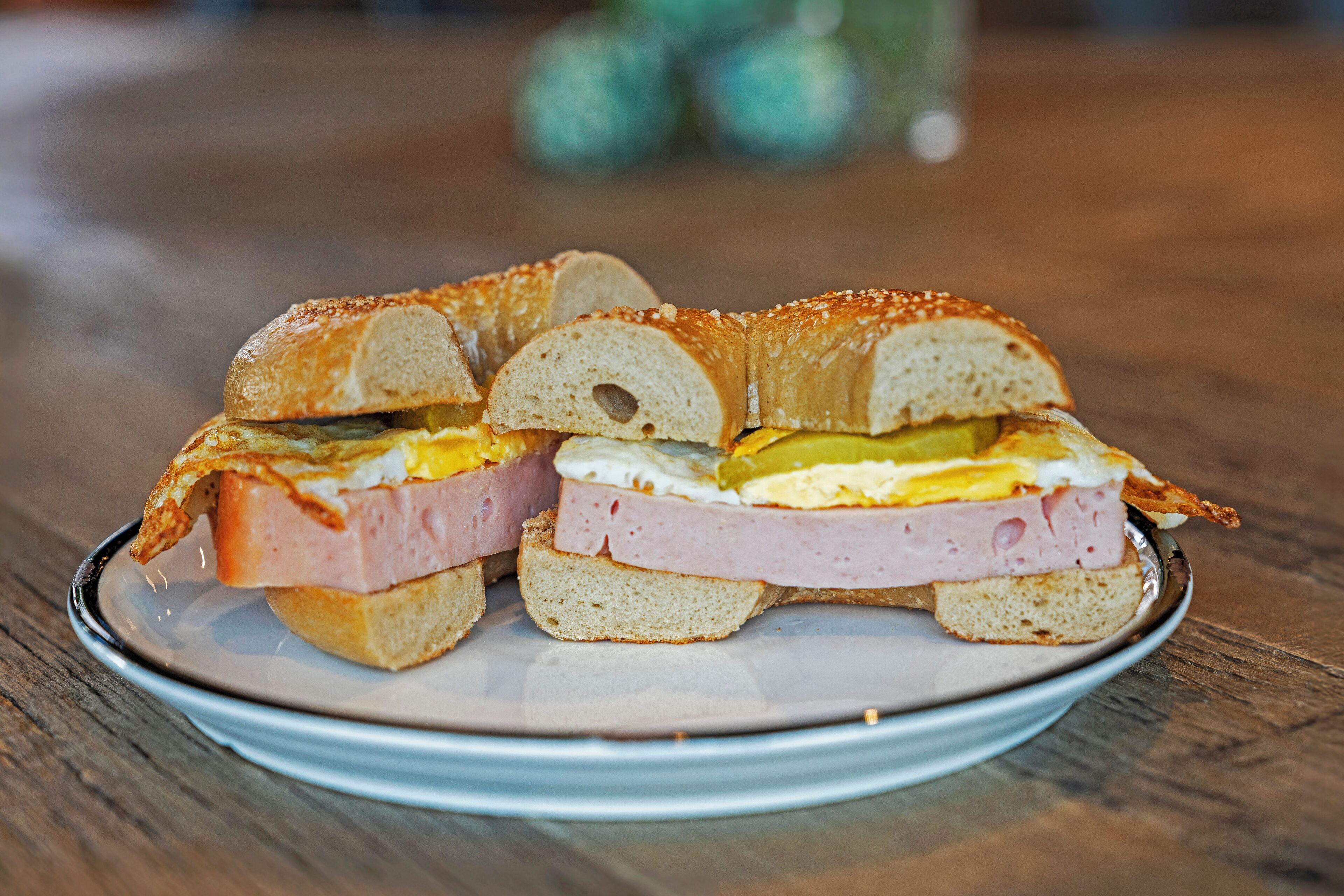 Un plato con un sándwich cortado por la mitad, con capas de jamón, queso y huevo.
